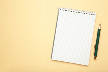 Bej arkaplanlı kalemli defter. Üst görünüm