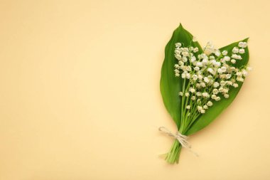 Mayıs çiçekleri. Bej arka planda bir buket nilüfer çiçeği. Mesaj için yer var. Üst görünüm