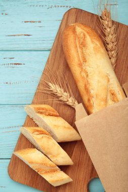 Ekmek bir bütün ve mavi ahşap arka planda tahta keserek parçalara ayrılmış. Dikey fotoğraf