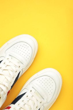 Beyaz ayakkabılar, sarı arka planda spor ayakkabılar. Uniseks spor ayakkabıları.