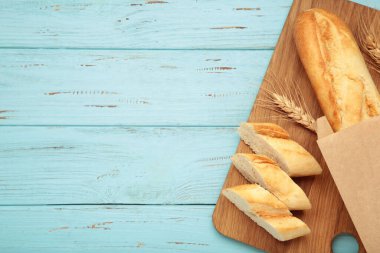 Ekmek bir bütün ve mavi ahşap arka planda tahta keserek parçalara ayrılmış. Metin için boşluk