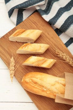 Ekmek bir bütün ve beyaz ahşap arka planda tahtayı keserek parçalara ayrılmış. Metin için boşluk