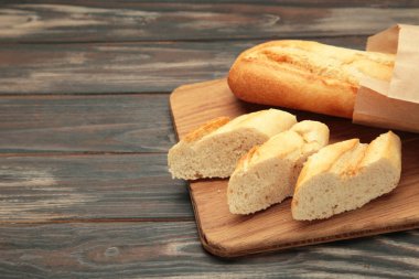 Ekmek bir bütün ve kahverengi arka planda kesme tahtasıyla parçalara ayrılmış. Metin için boşluk