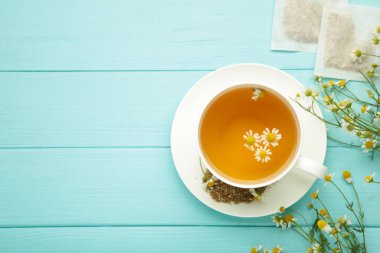 Papatya çayı poşeti, mavi ahşap arka planda papatya çiçekli bitkisel papatya çayı. Bağışıklık sistemi. Üst görünüm