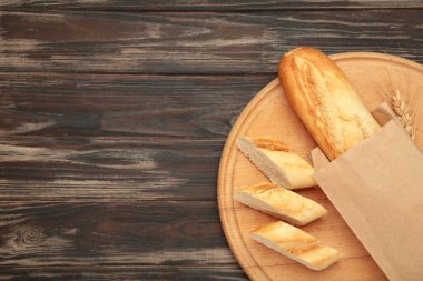 Ekmek bir bütün ve kahverengi ahşap arka planda tahta keserek parçalara ayrılmış. Metin için boşluk