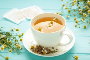 Papatya çayı poşeti, mavi ahşap arka planda papatya çiçekli bitkisel papatya çayı. Bağışıklık sistemi. Üst görünüm