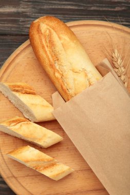 Ekmek bir bütün ve kahverengi ahşap arka planda tahta keserek parçalara ayrılmış. Metin için boşluk