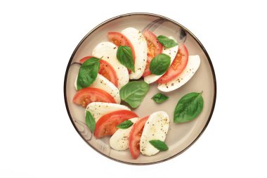 Çeri domatesli İtalyan Caprese salatası, mozzarella, beyaz arka planda izole edilmiş bir tabakta fesleğen. Üst görünüm