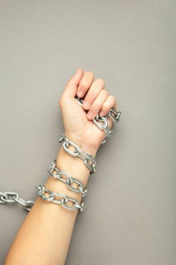 Elleri zincire vurulmuş gri arka planda. Üst görünüm