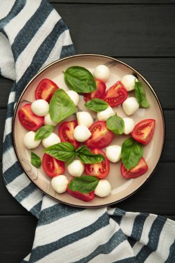 Çeri domatesli İtalyan Caprese salatası mozzarella, siyah arka planda fesleğen. Üst görünüm