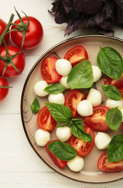 Çeri domatesli İtalyan Caprese salatası, mozzarella, beyaz arka planda fesleğen. Üst görünüm