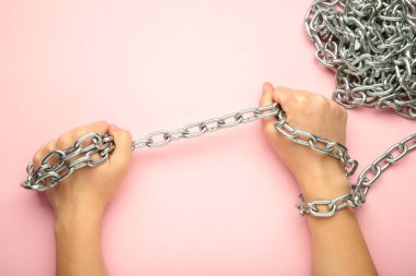 Elleri pembe arka planda zincirlenmiş. Üst görünüm