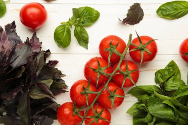 Beyaz ahşap arka planda fesleğen yapraklı taze kiraz domatesleri. Üst görünüm