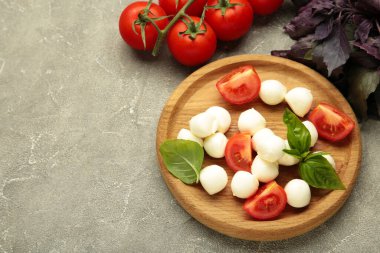 Çeri domatesli İtalyan Caprese salatası mozzarella, gri arka planda fesleğen. Üst görünüm