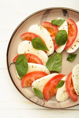 Çeri domatesli İtalyan Caprese salatası, mozzarella, beyaz arka planda fesleğen. Dikey fotoğraf