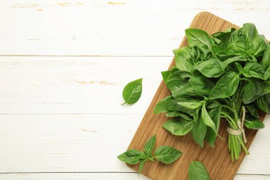 Beyaz ahşap arka planda taze yeşil fesleğen yaprakları. Üst görünüm