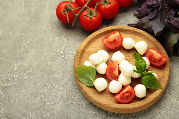 Çeri domatesli İtalyan Caprese salatası mozzarella, gri arka planda fesleğen. Üst görünüm