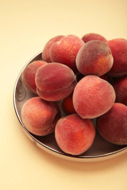 Tatlı şeftali ve yapraklar siyah tabakta bej arka planda. Üst görünüm