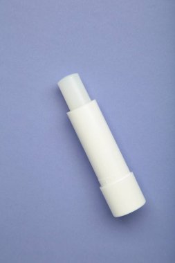 Mor arka planda dudak kremi. Dikey fotoğraf. Üst görünüm