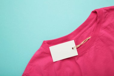 Mavi arka planda pembe tişörtün üzerinde fiyat etiketi var. Üst görünüm