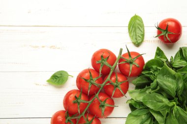 Beyaz ahşap arka planda fesleğen yapraklı taze kiraz domatesleri. Üst görünüm