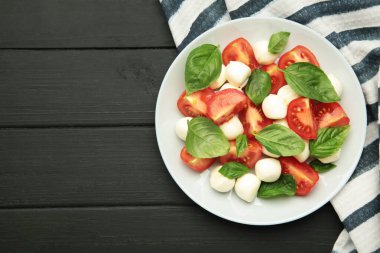 Çeri domatesli İtalyan Caprese salatası mozzarella, siyah arka planda fesleğen. Üst görünüm