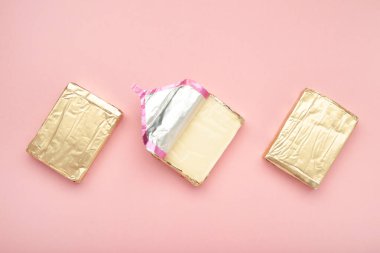 Pembe arka planda folyoyla işlenmiş peynir. Üst görünüm