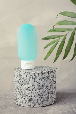 Gri arka planda yeşil yapraklı kozmetik şişesi. Mesaj için yer var. Üst görünüm