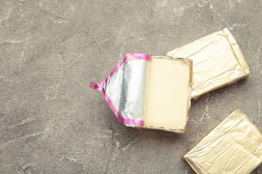 Gri arka planda folyoyla işlenmiş peynir. Üst görünüm