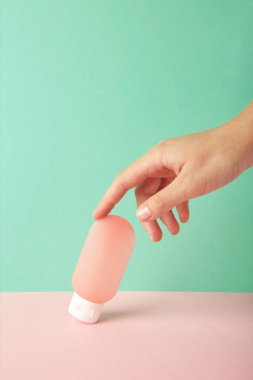 Nane arkaplanda boş pembe plastik bir tüp tutuyor. Kozmetik güzellik ürünü markalaşma modeli.