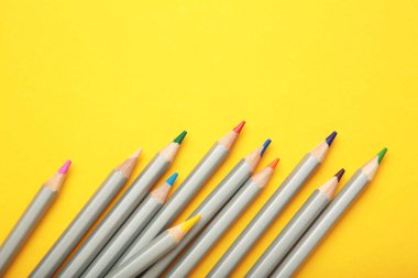 Sarı arka planda bir sürü renkli kalem var. Üst görünüm