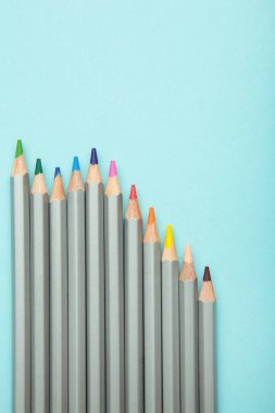 Mavi arka planda bir sürü renkli kalem var. Üst görünüm