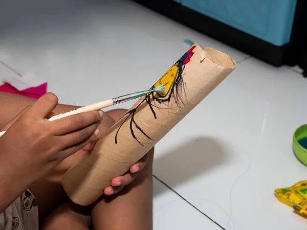 Kids painting on a paper tube