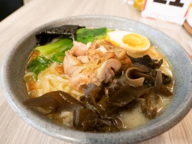 Ahşap bir masaya konmuş gri bir kasede ramen.