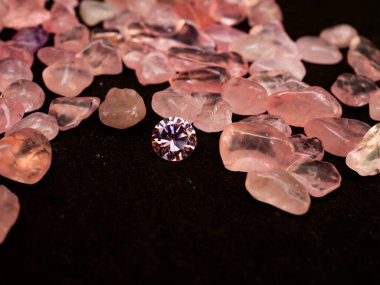 Güzel yuvarlak kesim, siyah arka planda pembe renkli elmas.