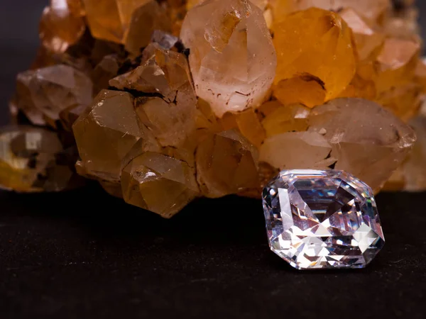 Sparkling asscher cut diamond with rough citrine stone as background