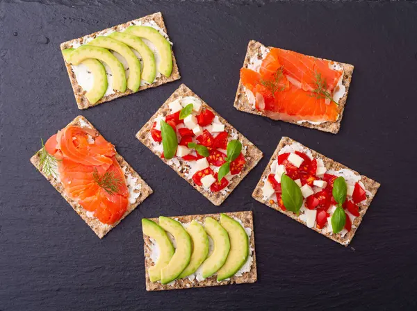 stock image Protein toast ceispbread with delicious toppings top view : avocado, salmon, vegetables, tomatoes, herbs and cheese