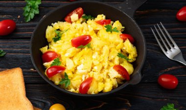 Sağlıklı vejetaryen kahvaltısı. Tavada yumurta, kiraz domatesli ve maydanozlu. Üst görünüm