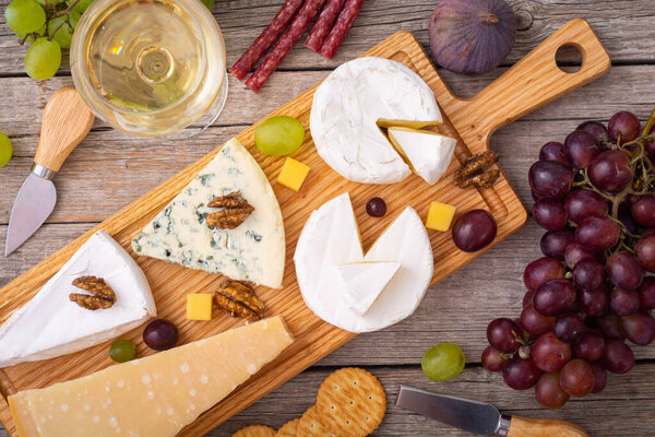 Differnt kind of cheese on the wooden board . Top view