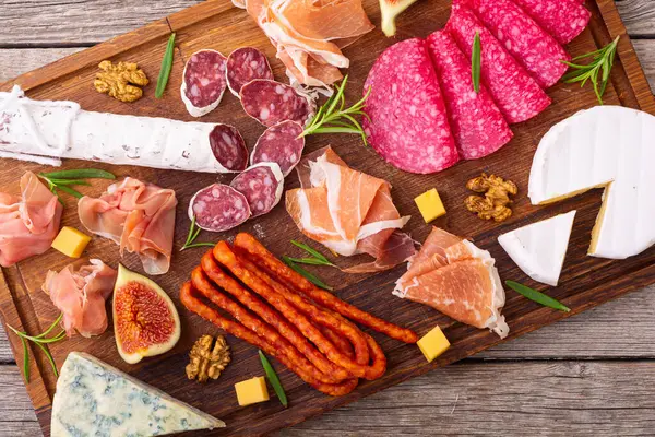 Board with meat, sausages and cheese . Top view food background