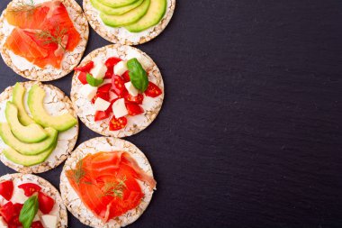 Lezzetli soslu protein tostu: avokado, somon, sebze, domates, otlar ve peynir.