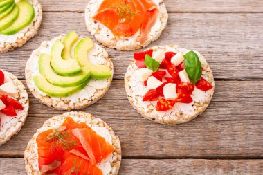 Lezzetli soslu protein tostu: avokado, somon, sebze, domates, otlar ve peynir.