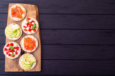 Lezzetli soslu protein tostu: avokado, somon, sebze, domates, otlar ve peynir.