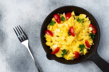Sağlıklı vejetaryen kahvaltısı. Tavada yumurta, kiraz domatesli ve maydanozlu. Üst görünüm