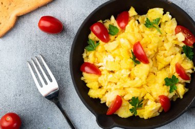 Sağlıklı vejetaryen kahvaltısı. Tavada yumurta, kiraz domatesli ve maydanozlu. Üst görünüm