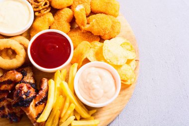 Soğan halkaları, kızarmış kanatlar, patates kızartması ve soslar. Bira tahtası