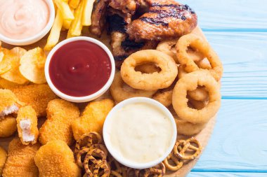 Soğan halkaları, kızarmış kanatlar, patates kızartması ve soslar. Bira tahtası