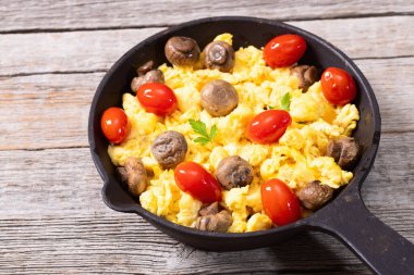 Sağlıklı vejetaryen kahvaltısı. Tavada yumurta, kiraz domatesli ve maydanozlu. Üst görünüm