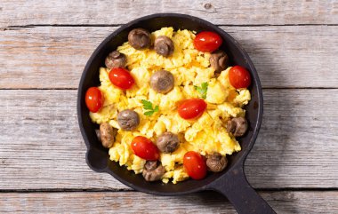 Sağlıklı vejetaryen kahvaltısı. Tavada yumurta, kiraz domatesli ve maydanozlu. Üst görünüm