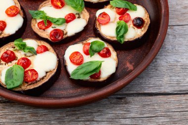 İtalyan mini pizzası. Patlıcan peynirli ve fesleğenli. Kırsal arkaplan üstü görünümünde